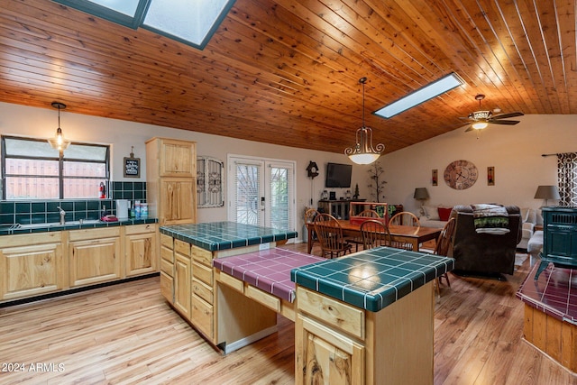 kitchen with a center island, ceiling fan, tile countertops, and light wood-type flooring