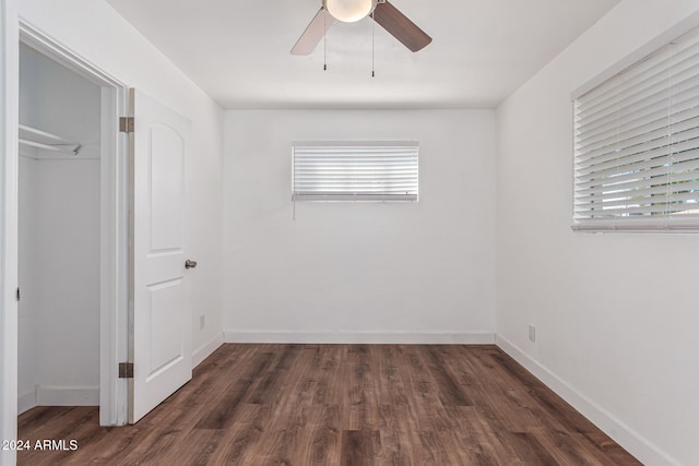 unfurnished bedroom featuring a closet, ceiling fan, dark hardwood / wood-style flooring, and a walk in closet