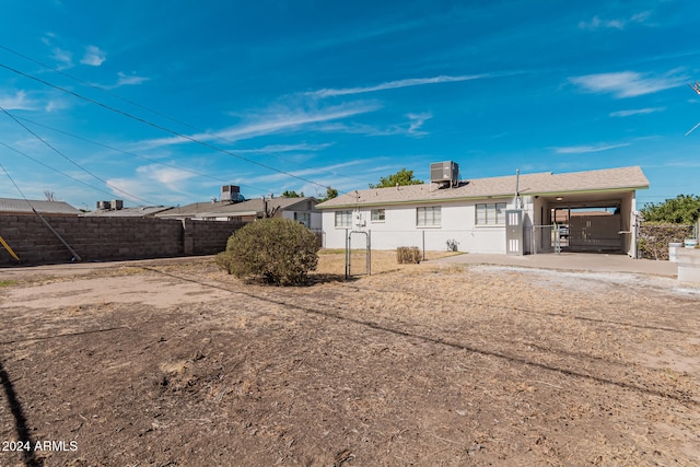 back of house with central air condition unit and a carport