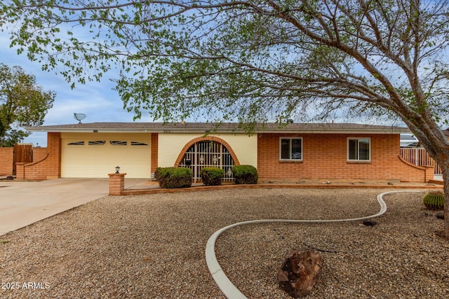 ranch-style house with brick siding, an attached garage, driveway, and fence