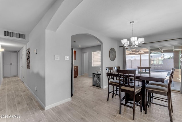 dining area with light hardwood / wood-style flooring and a notable chandelier