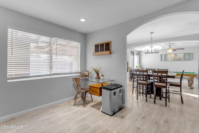 dining room featuring ceiling fan with notable chandelier and light hardwood / wood-style flooring