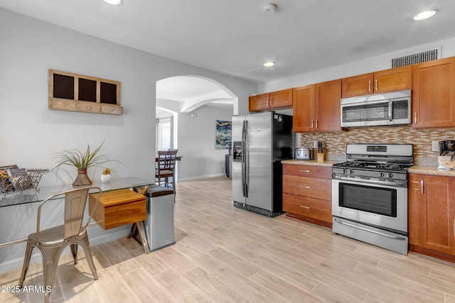 kitchen with backsplash, stainless steel appliances, and light hardwood / wood-style flooring