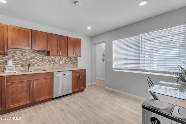 kitchen featuring light stone countertops, dishwasher, sink, tasteful backsplash, and light wood-type flooring