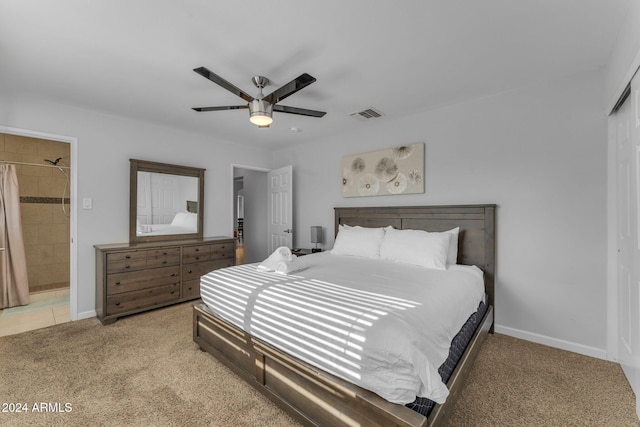 bedroom with light carpet, a closet, ensuite bathroom, and ceiling fan