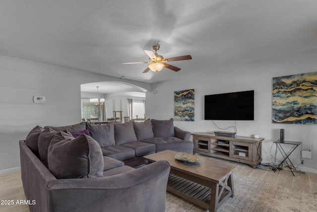 living room featuring ceiling fan with notable chandelier and light hardwood / wood-style floors