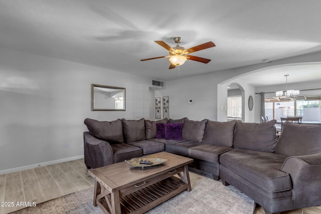 living room featuring ceiling fan with notable chandelier and light hardwood / wood-style flooring