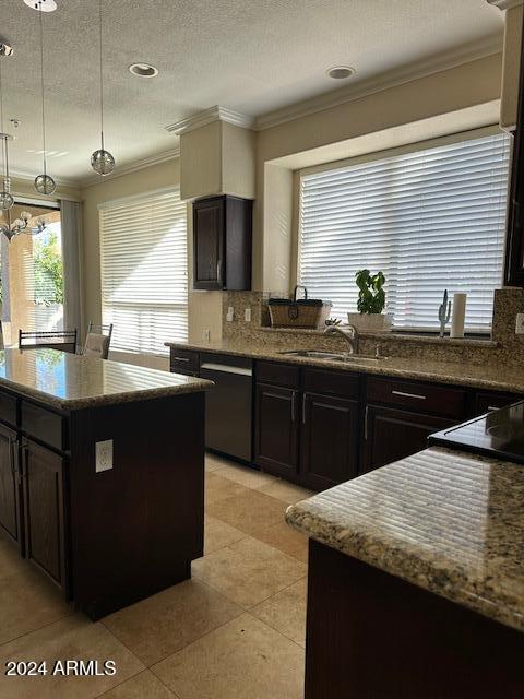 kitchen featuring crown molding, sink, hanging light fixtures, light tile patterned floors, and a textured ceiling