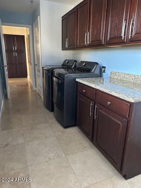 laundry room featuring washer and dryer, light tile patterned floors, and cabinets