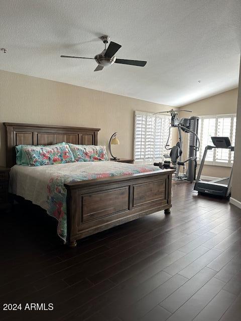 bedroom with ceiling fan, dark hardwood / wood-style flooring, a textured ceiling, and vaulted ceiling