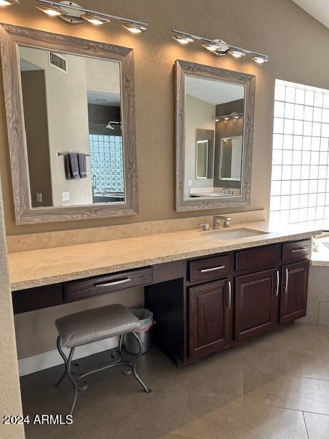 bathroom with tile patterned floors, a tub, a healthy amount of sunlight, and vaulted ceiling