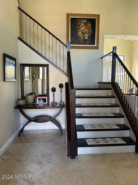 stairs with tile patterned flooring and a high ceiling