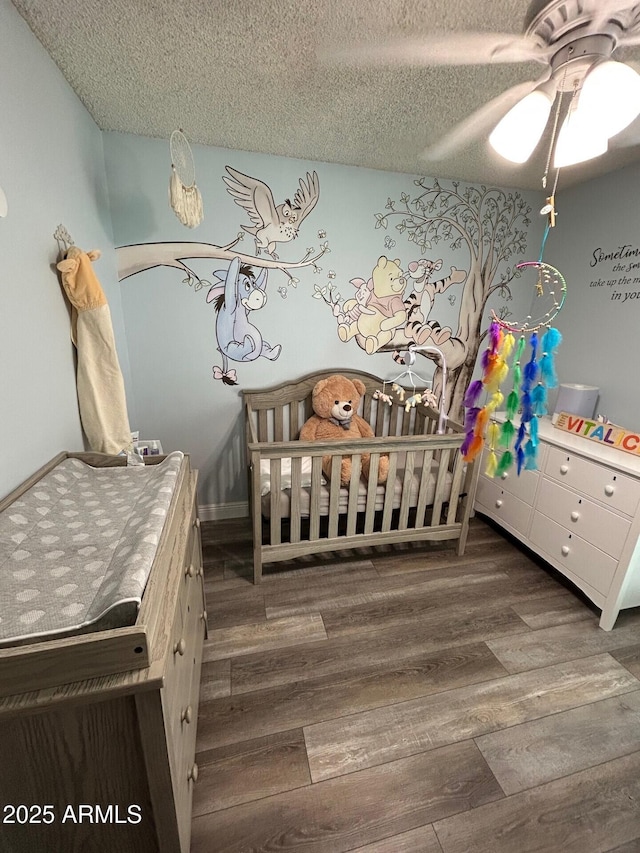 5143 W Mountain View Rd, Glendale, AZ 85302 - bedroom featuring wood finished floors, a textured ceiling, a ceiling fan, and a crib