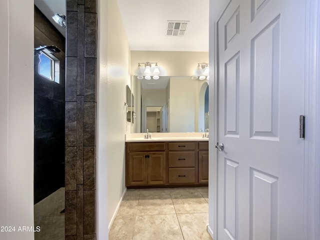 bathroom with a tile shower, tile patterned flooring, and vanity