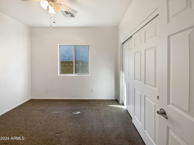 unfurnished bedroom with ceiling fan, a closet, and dark colored carpet