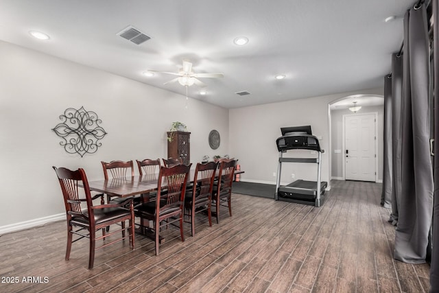 dining area featuring arched walkways, visible vents, dark wood-type flooring, ceiling fan, and baseboards