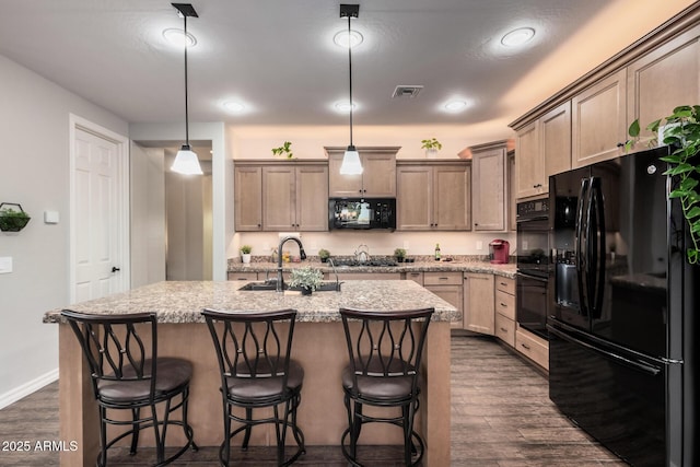 kitchen featuring dark wood-style flooring, a center island with sink, visible vents, a sink, and black appliances