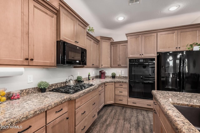 kitchen with dark wood-style floors, black appliances, light stone counters, and recessed lighting