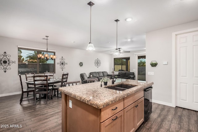 kitchen with pendant lighting, dark wood-style flooring, a center island with sink, a sink, and dishwasher