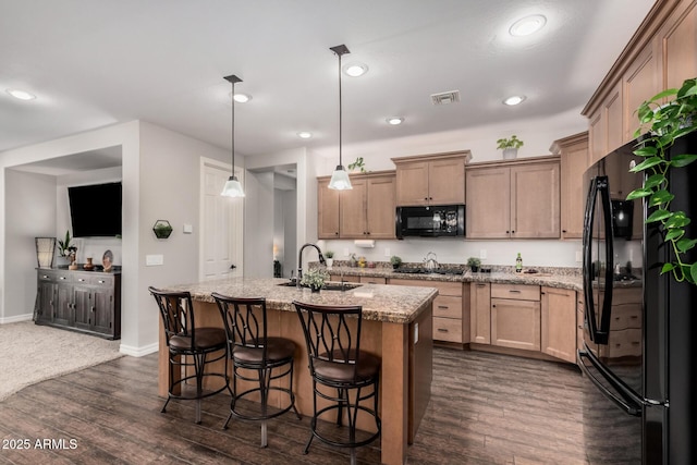 kitchen with a kitchen breakfast bar, dark wood-style flooring, a sink, and black appliances