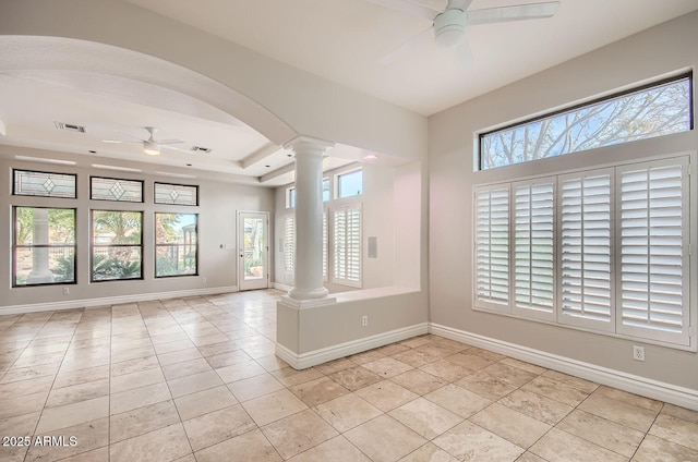 empty room featuring a healthy amount of sunlight, light tile patterned floors, ceiling fan, and ornate columns