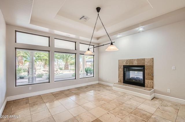 unfurnished living room with light tile patterned flooring, a fireplace, and a raised ceiling