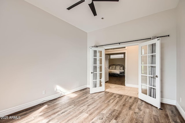 spare room with light hardwood / wood-style flooring, ceiling fan, and french doors