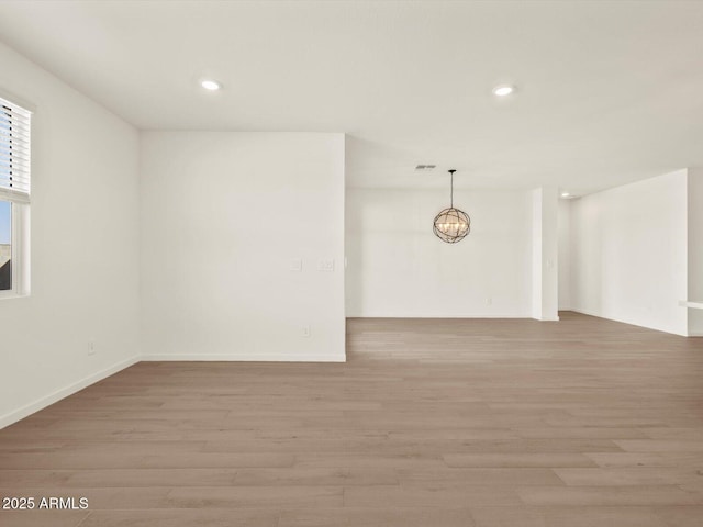 empty room with a notable chandelier and light hardwood / wood-style flooring