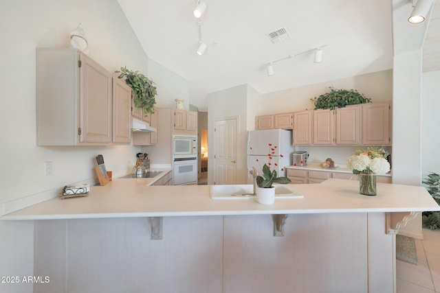 kitchen with lofted ceiling, a breakfast bar area, white appliances, and kitchen peninsula