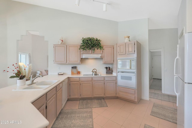 kitchen featuring white appliances, sink, a high ceiling, and light brown cabinets