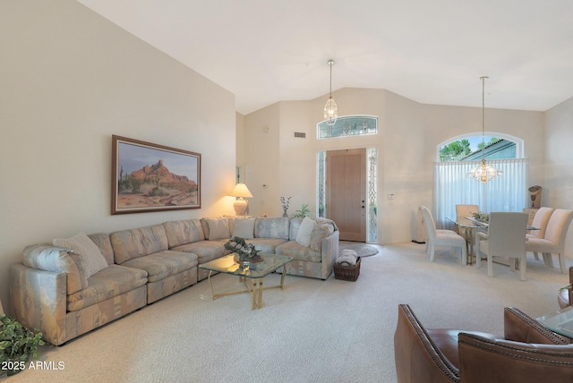 carpeted living room with high vaulted ceiling and a chandelier