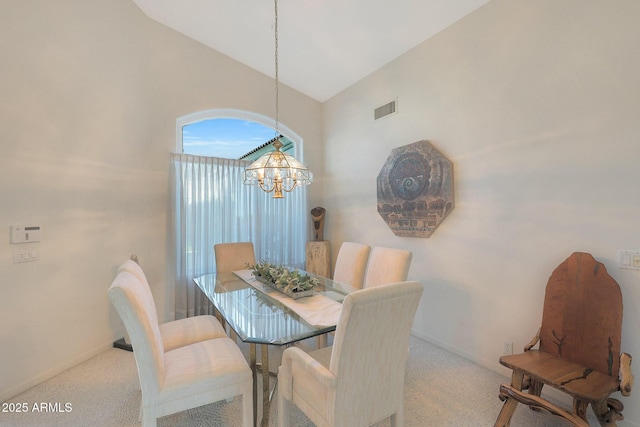 carpeted dining space featuring a notable chandelier and high vaulted ceiling