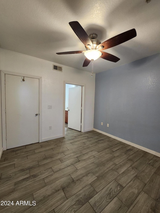 unfurnished bedroom with a textured ceiling, dark hardwood / wood-style flooring, ceiling fan, and a closet