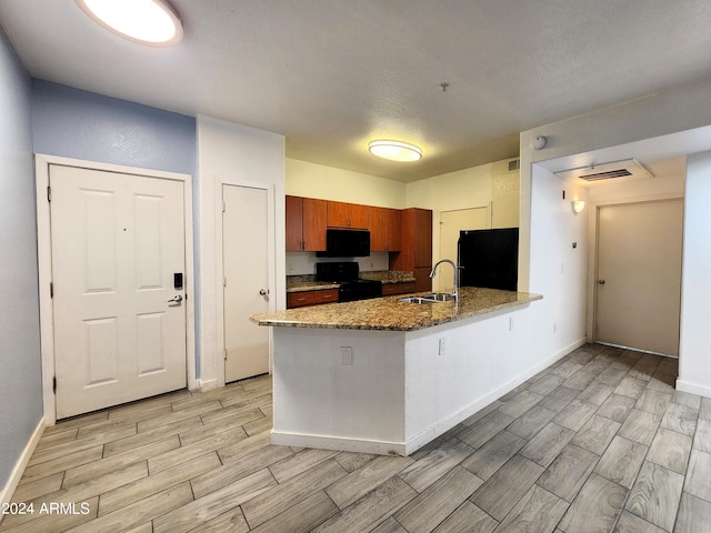 kitchen featuring sink, kitchen peninsula, stone countertops, black appliances, and light hardwood / wood-style floors