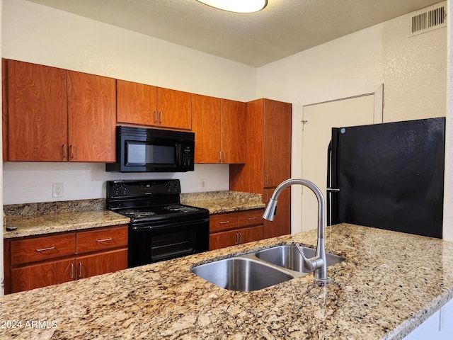 kitchen with a textured ceiling, black appliances, sink, and light stone countertops