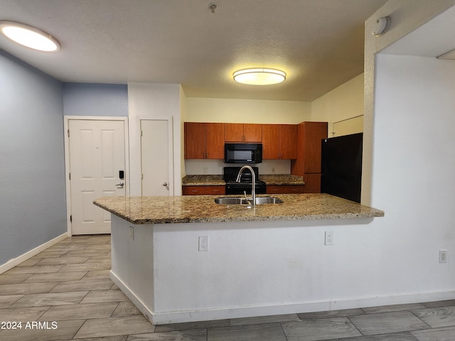 kitchen with kitchen peninsula, light stone countertops, a textured ceiling, black appliances, and sink