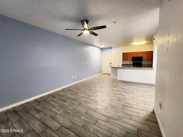 unfurnished living room with light hardwood / wood-style floors, ceiling fan, and sink