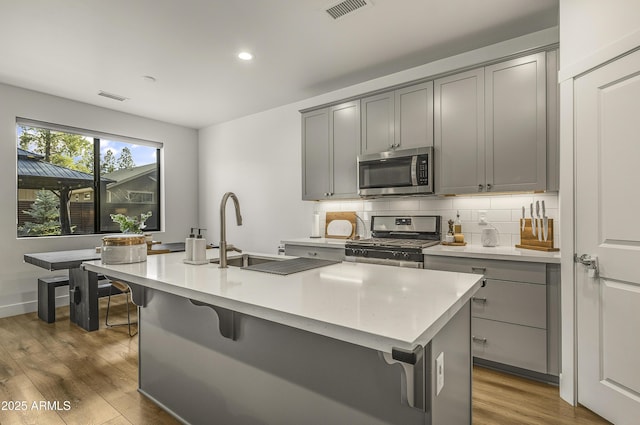 kitchen featuring gray cabinetry, appliances with stainless steel finishes, a sink, and visible vents