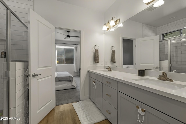 ensuite bathroom with connected bathroom, double vanity, a sink, and wood finished floors