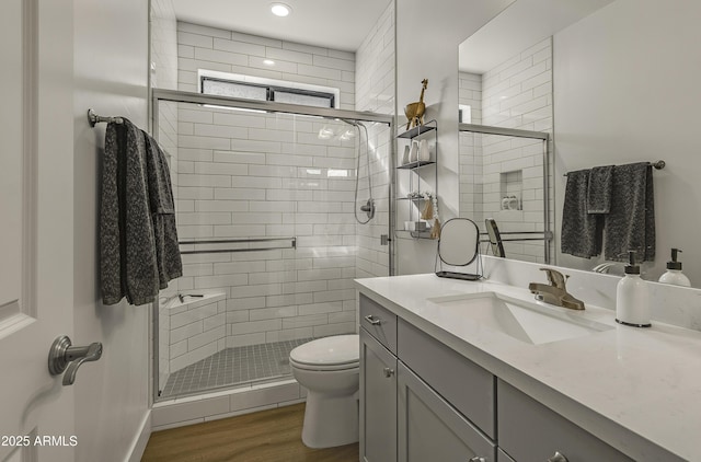 full bathroom with vanity, wood finished floors, toilet, and a shower stall