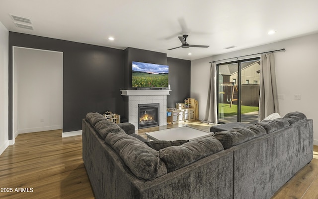 living area featuring baseboards, a ceiling fan, wood finished floors, and visible vents