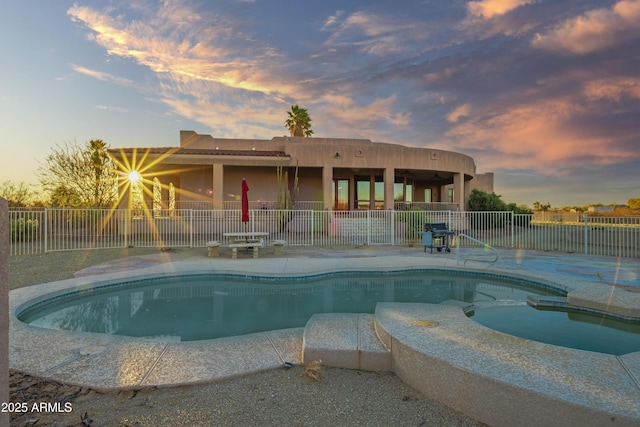 pool at dusk with a jacuzzi and a patio area