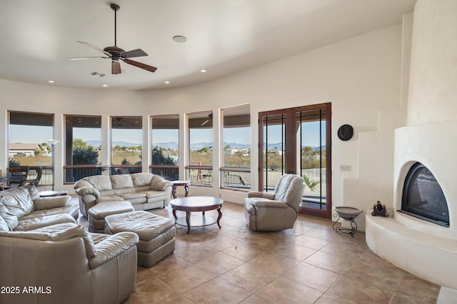 living room with a fireplace, ceiling fan, light tile patterned floors, and a mountain view