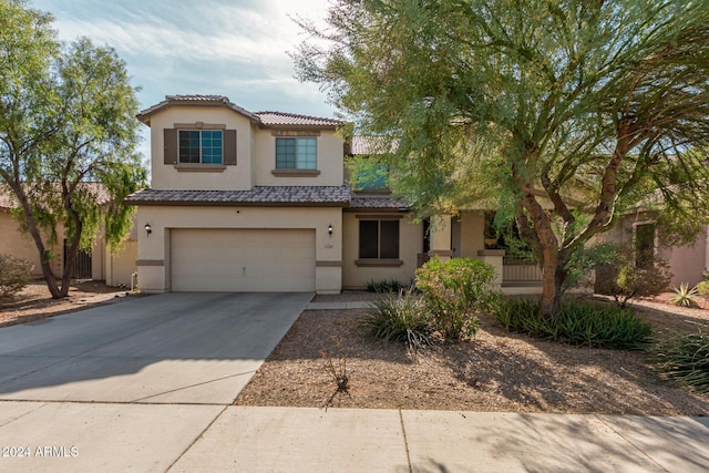 view of front of property featuring an attached garage, driveway, a tile roof, and stucco siding