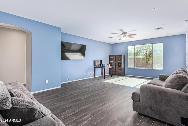 living room featuring arched walkways, wood finished floors, a ceiling fan, visible vents, and baseboards