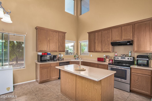 kitchen featuring appliances with stainless steel finishes, light countertops, under cabinet range hood, and a high ceiling
