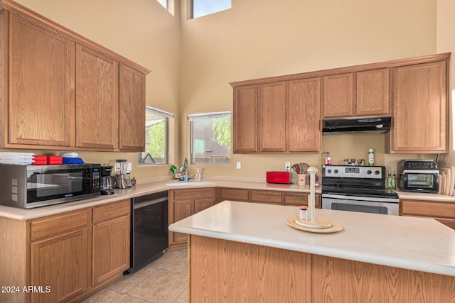 kitchen featuring light tile patterned floors, appliances with stainless steel finishes, light countertops, under cabinet range hood, and a sink