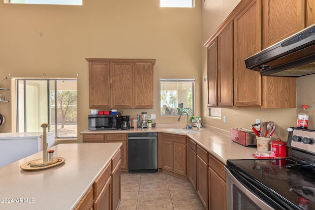 kitchen with under cabinet range hood, a sink, light countertops, stainless steel electric range, and dishwasher