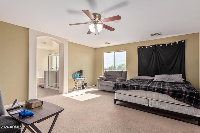 carpeted bedroom featuring a ceiling fan, arched walkways, visible vents, and ensuite bath