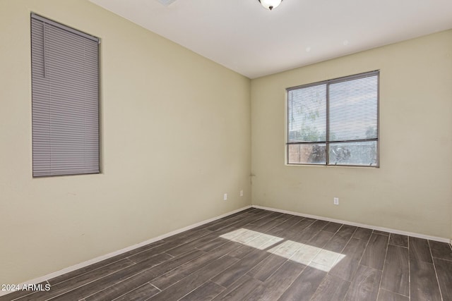 empty room with baseboards and dark wood finished floors
